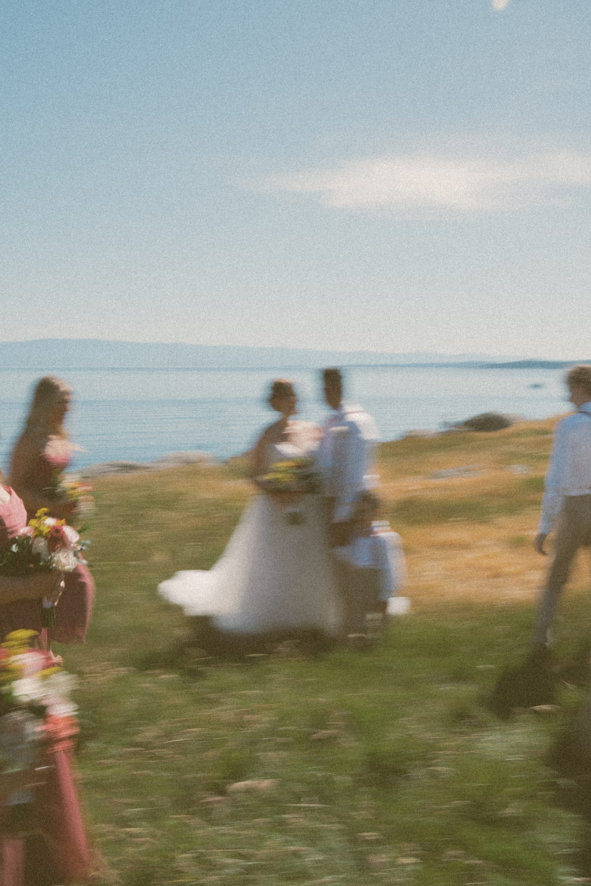 A candid, motion-blurred frame of Charlotte and Vis walking the grassy shoreline