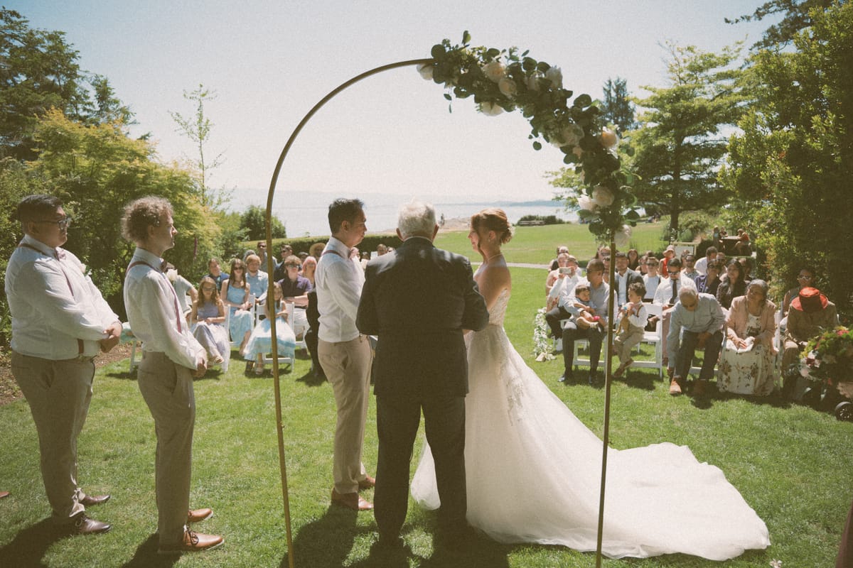 Ceremony at the floral arch overlooking the water at Saxe Point Park