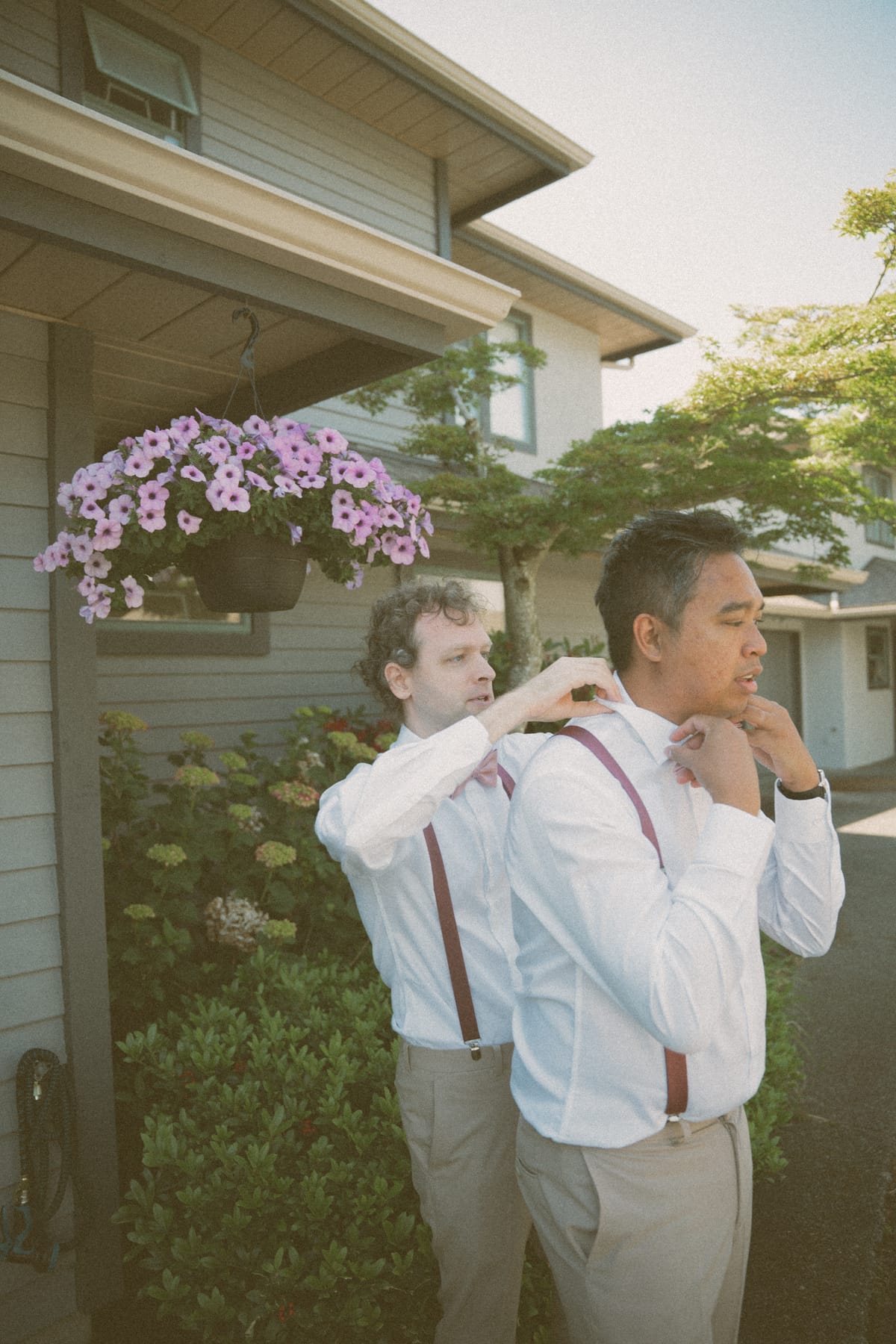 Vis and a groomsman adjusting their bow ties and suspenders outside before the ceremony