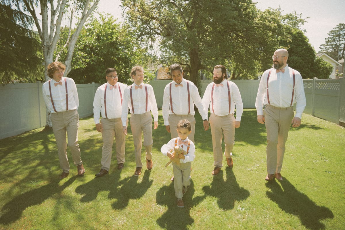 The groomsmen walking across the lawn with the young ring bearer leading the way