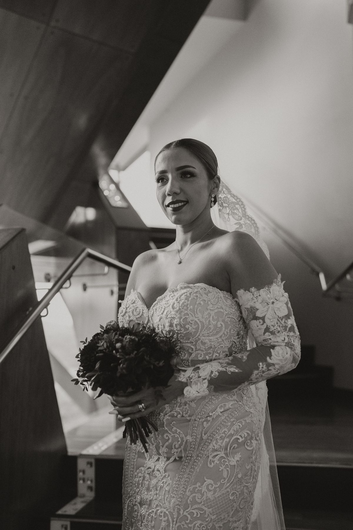 Black and white portrait of the bride on the staircase with her bouquet