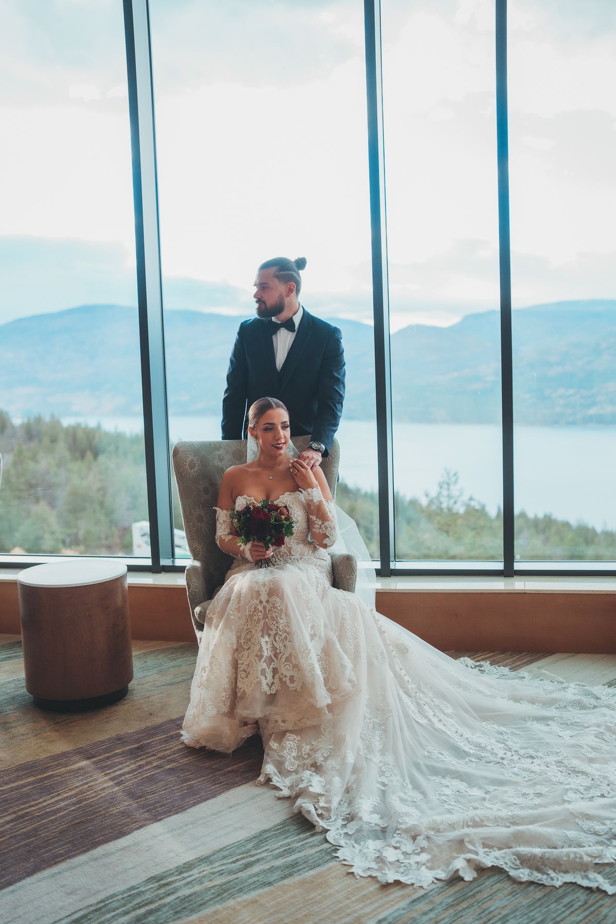 The couple framed by the resort's floor-to-ceiling windows over the lake