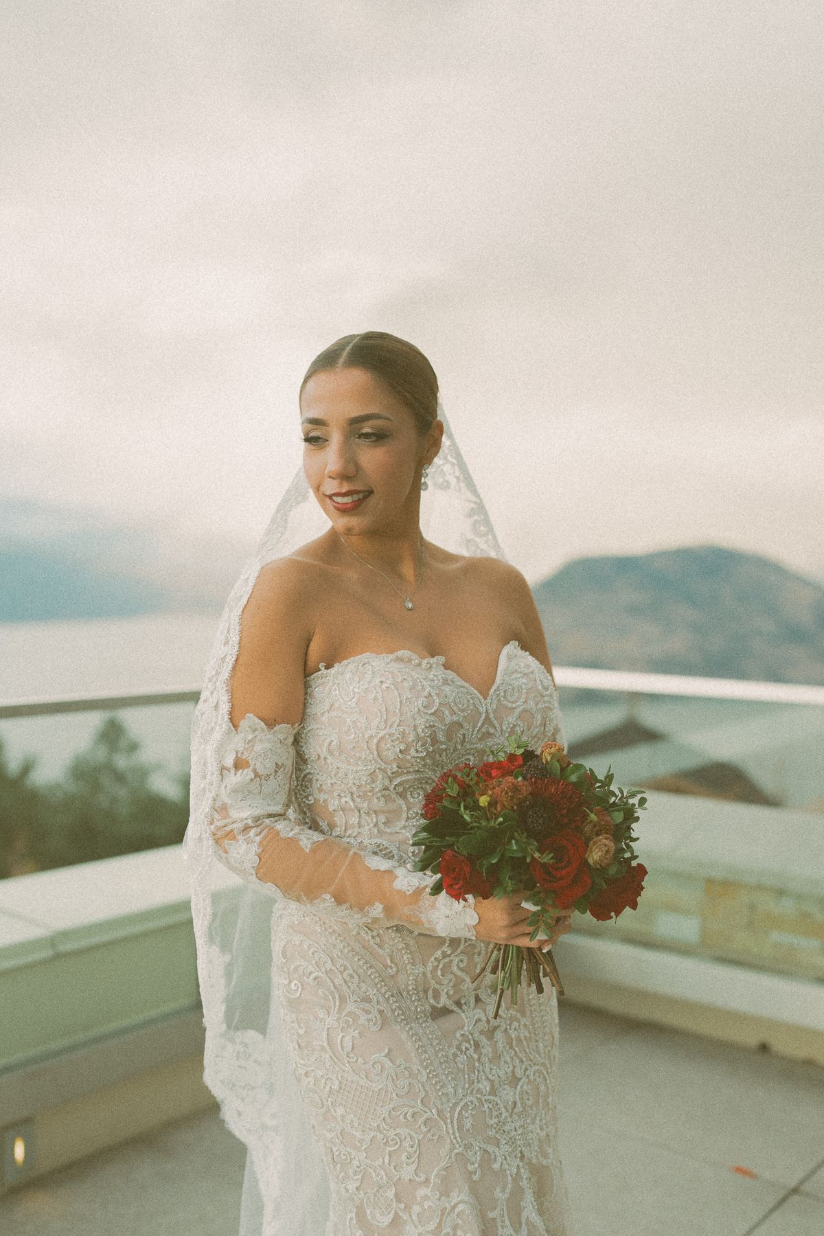 The bride with her red bouquet and long veil on the terrace