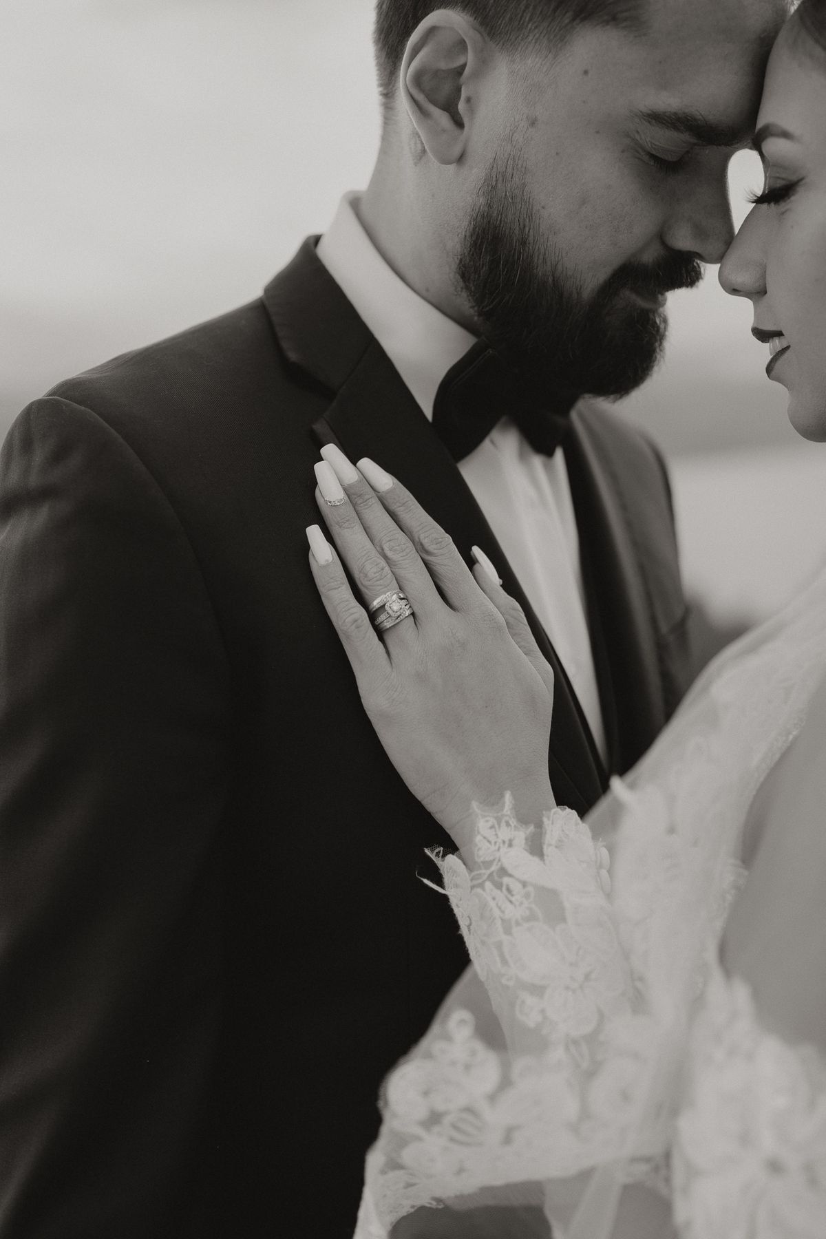 Black and white detail of the bride's ringed hand on the groom's chest