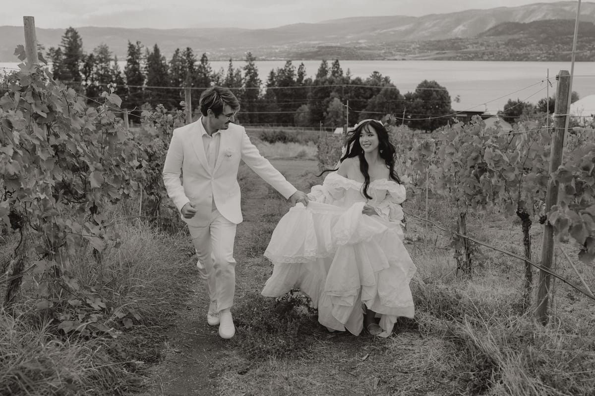 Black and white of Nina and Brandon walking the vineyard rows above Okanagan Lake