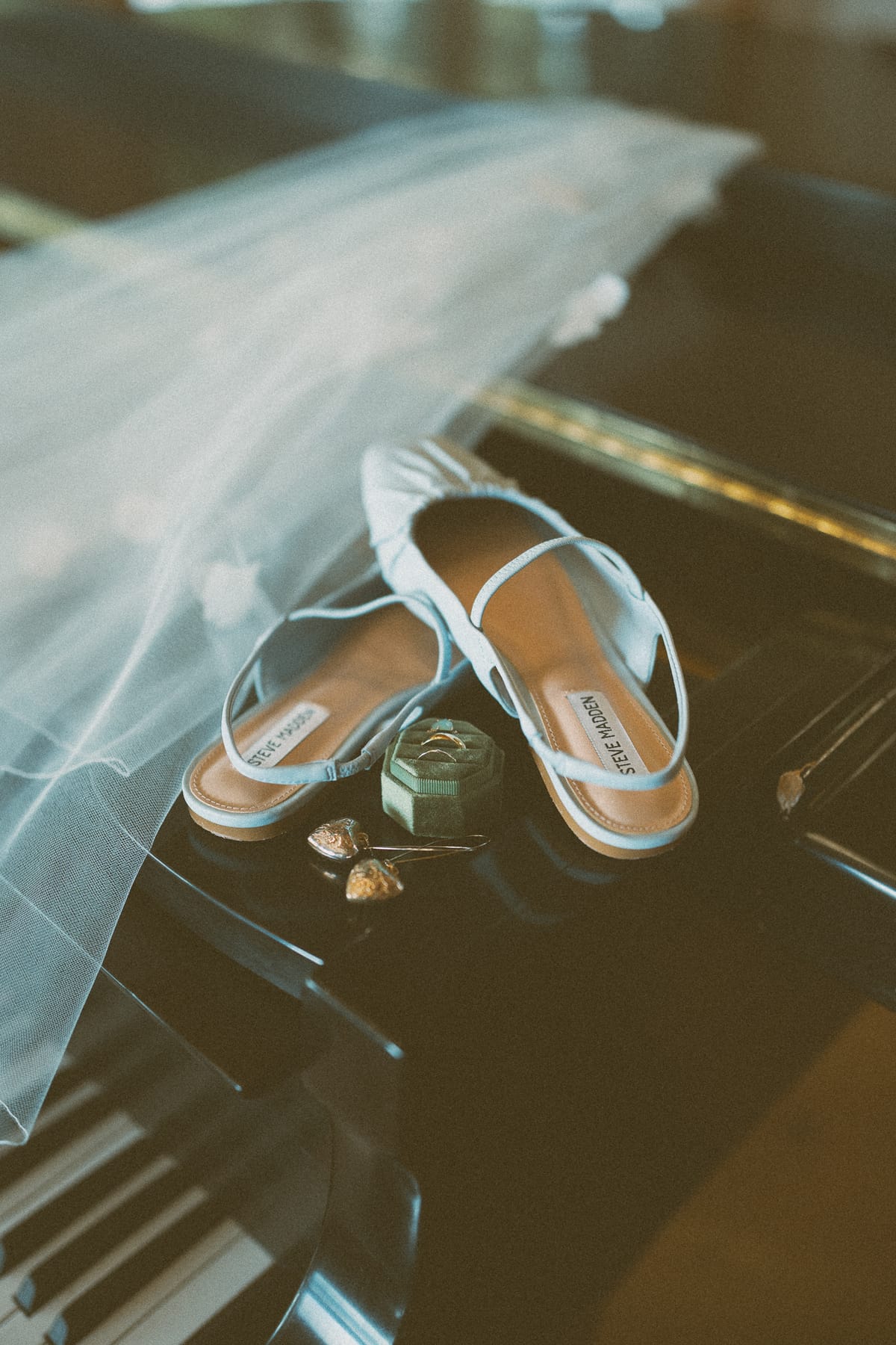 The bride's blue sandals and ring box resting on the piano beside her veil