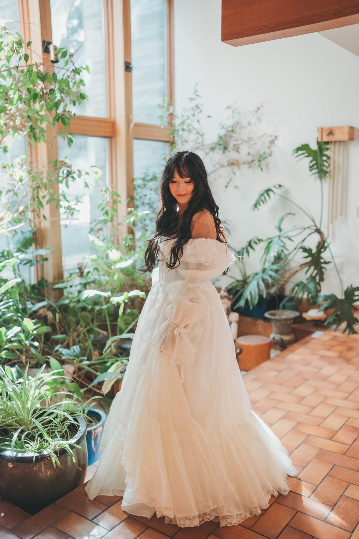 Full-length portrait of Nina in her tiered vintage gown on the terracotta tile of the atrium
