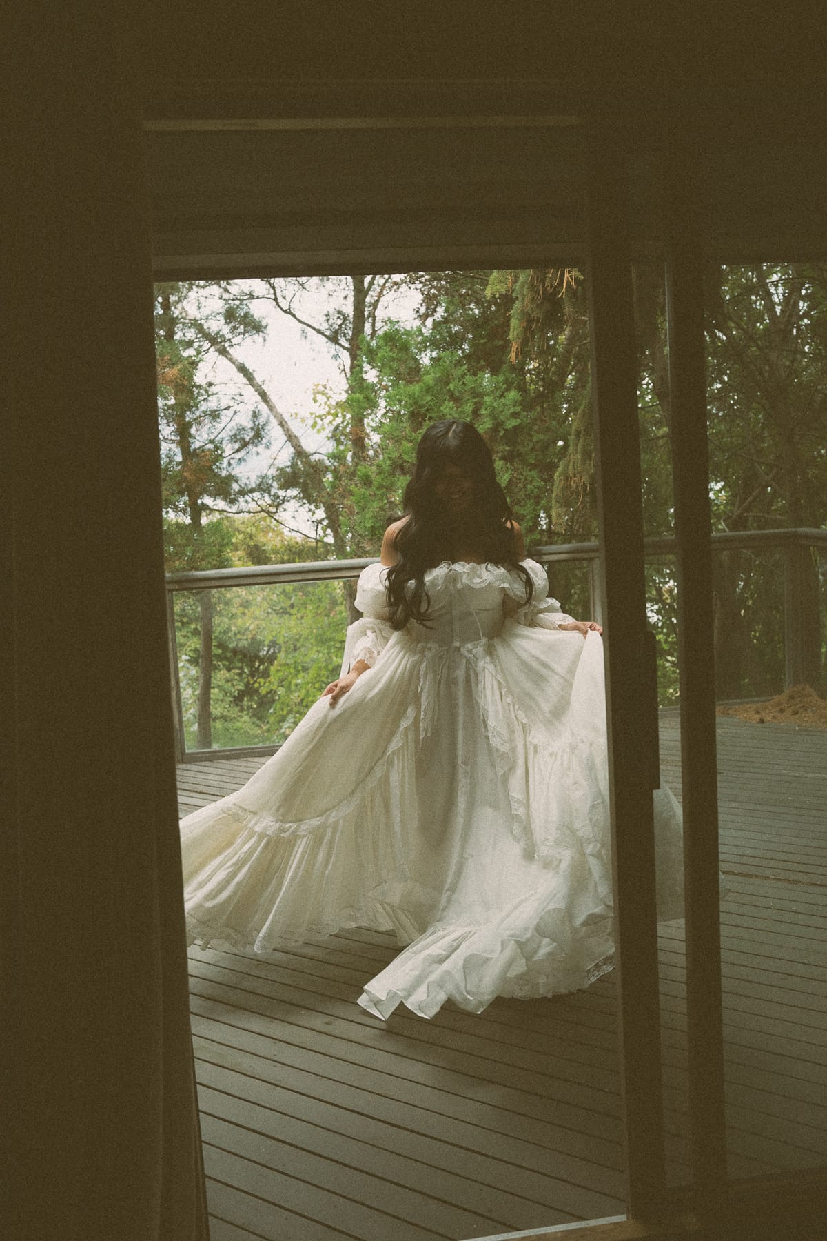 Nina on the deck framed through the doorway, her gown and veil flowing