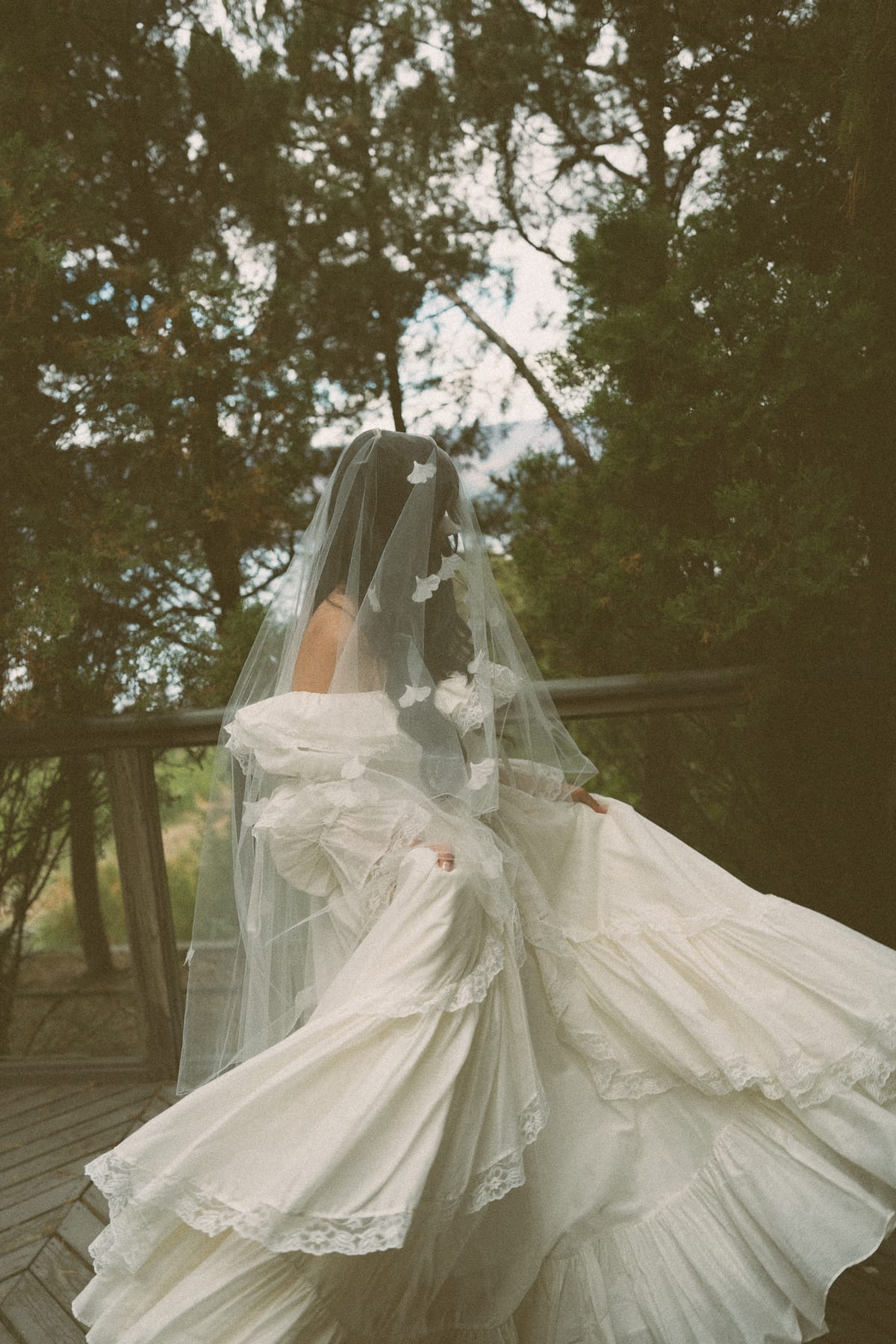 Nina twirling her gown and floral-appliqué veil on the deck