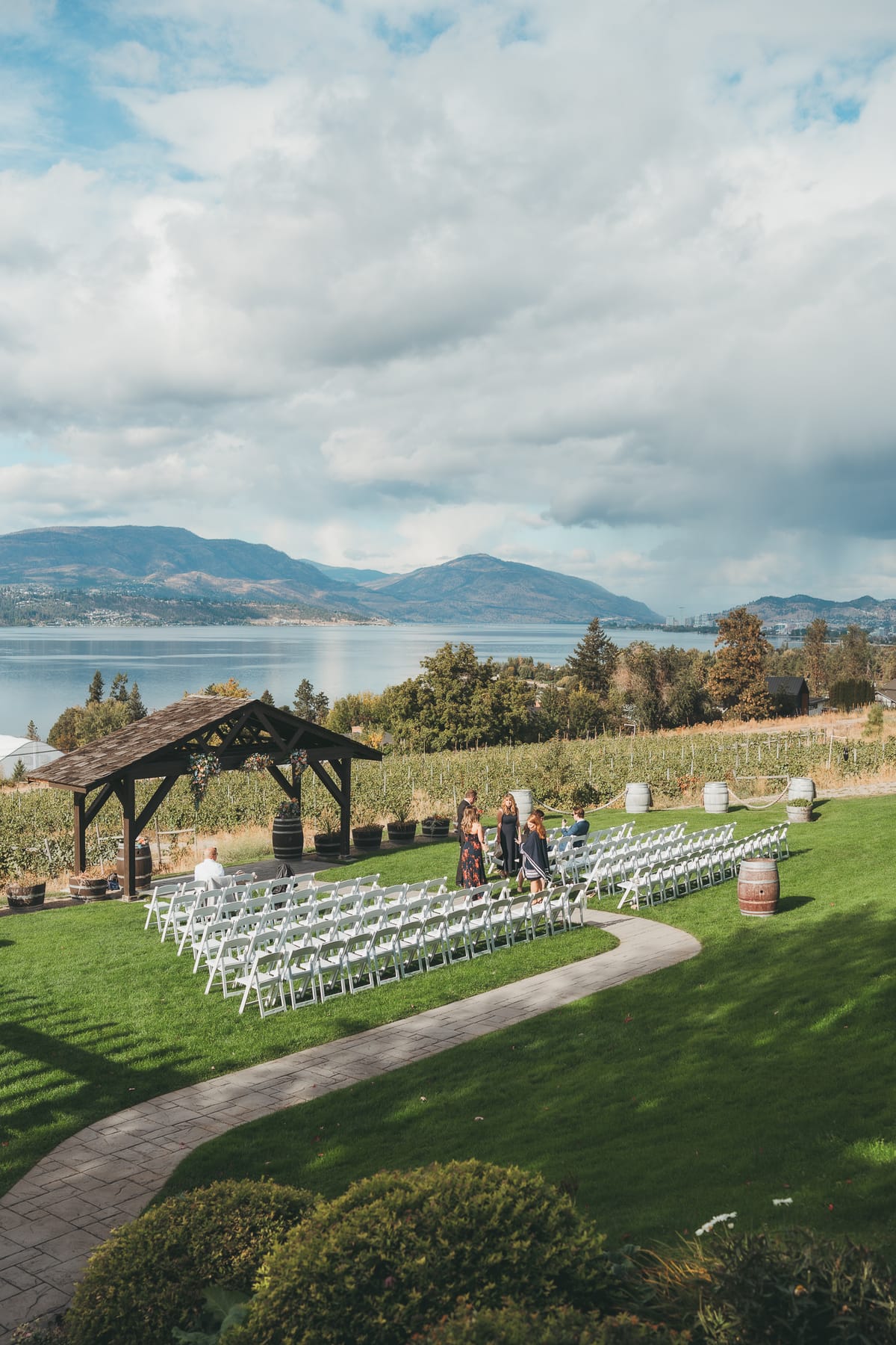 The ceremony set beneath the wooden pergola above the vineyard and Okanagan Lake
