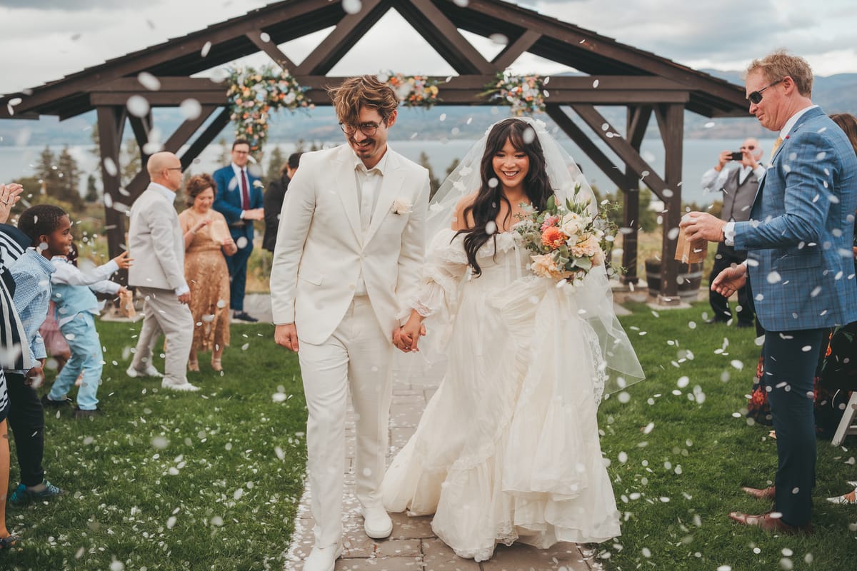 Nina and Brandon walking hand in hand through the confetti exit