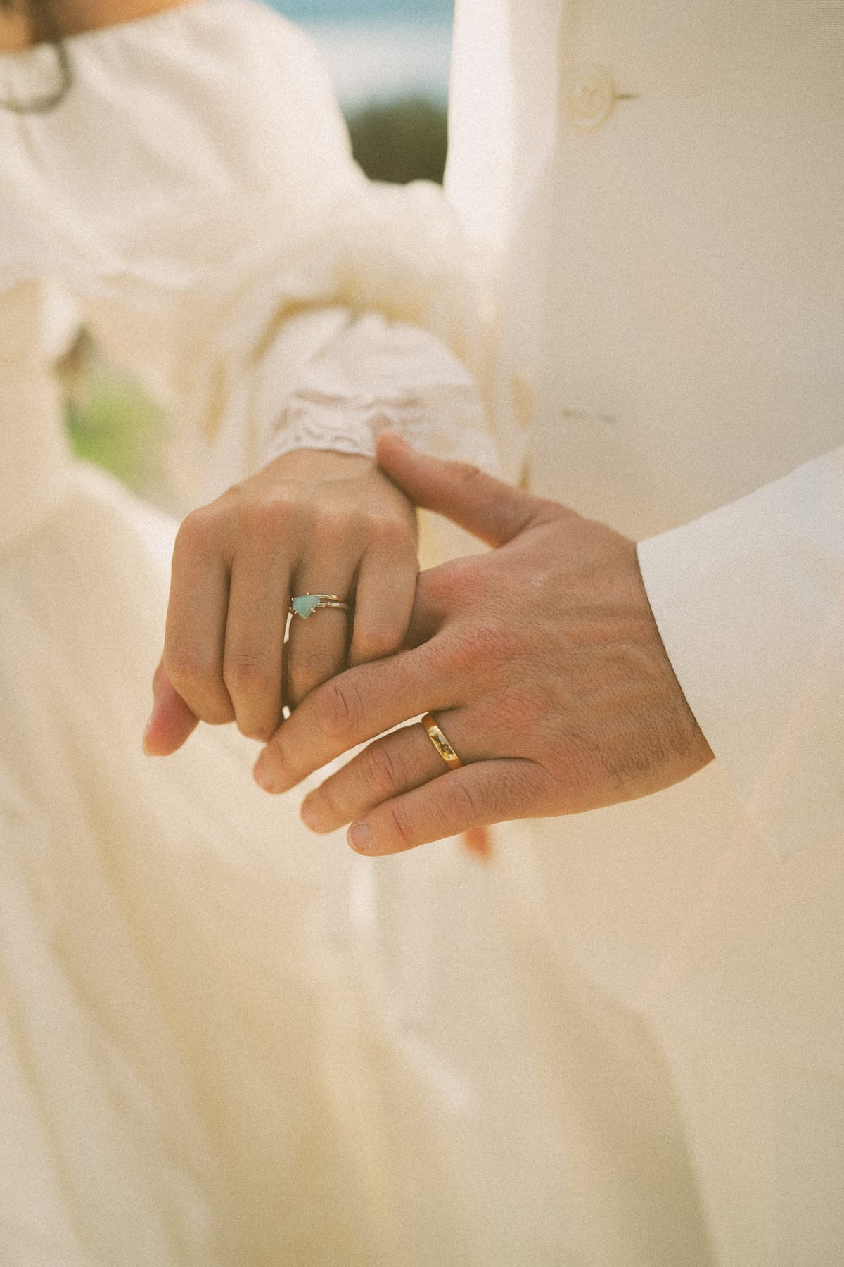 Detail of Nina and Brandon's hands with her raw aquamarine ring and his gold band