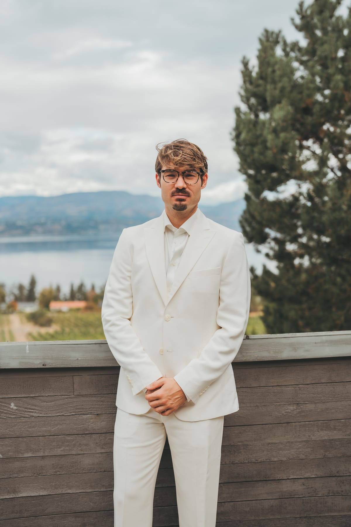 Brandon in his cream suit on the terrace with Okanagan Lake behind him