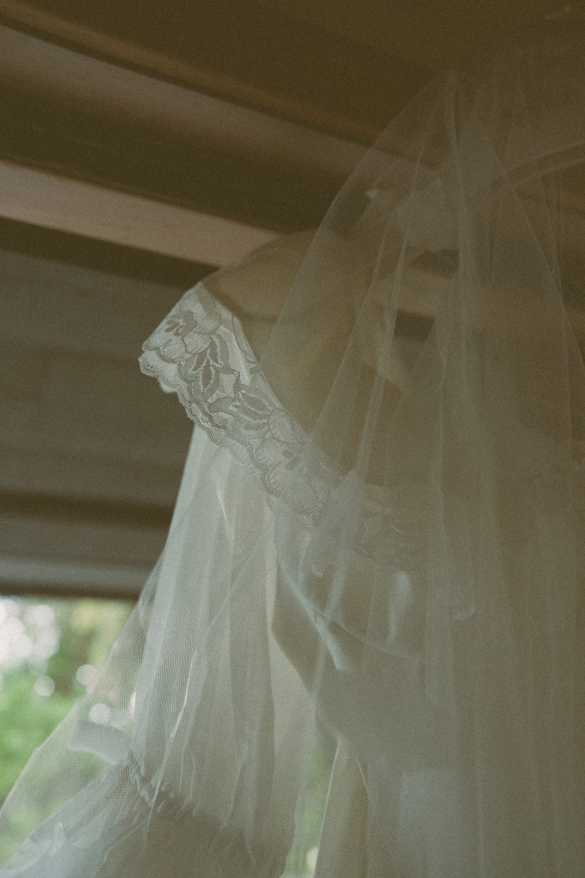 Soft detail of the gown's lace sleeve and veil in the window light