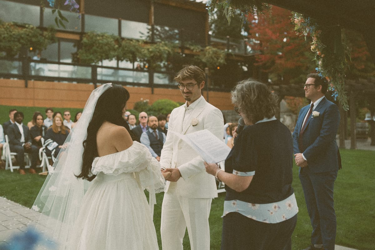 Nina and Brandon facing each other during the ceremony as guests look on