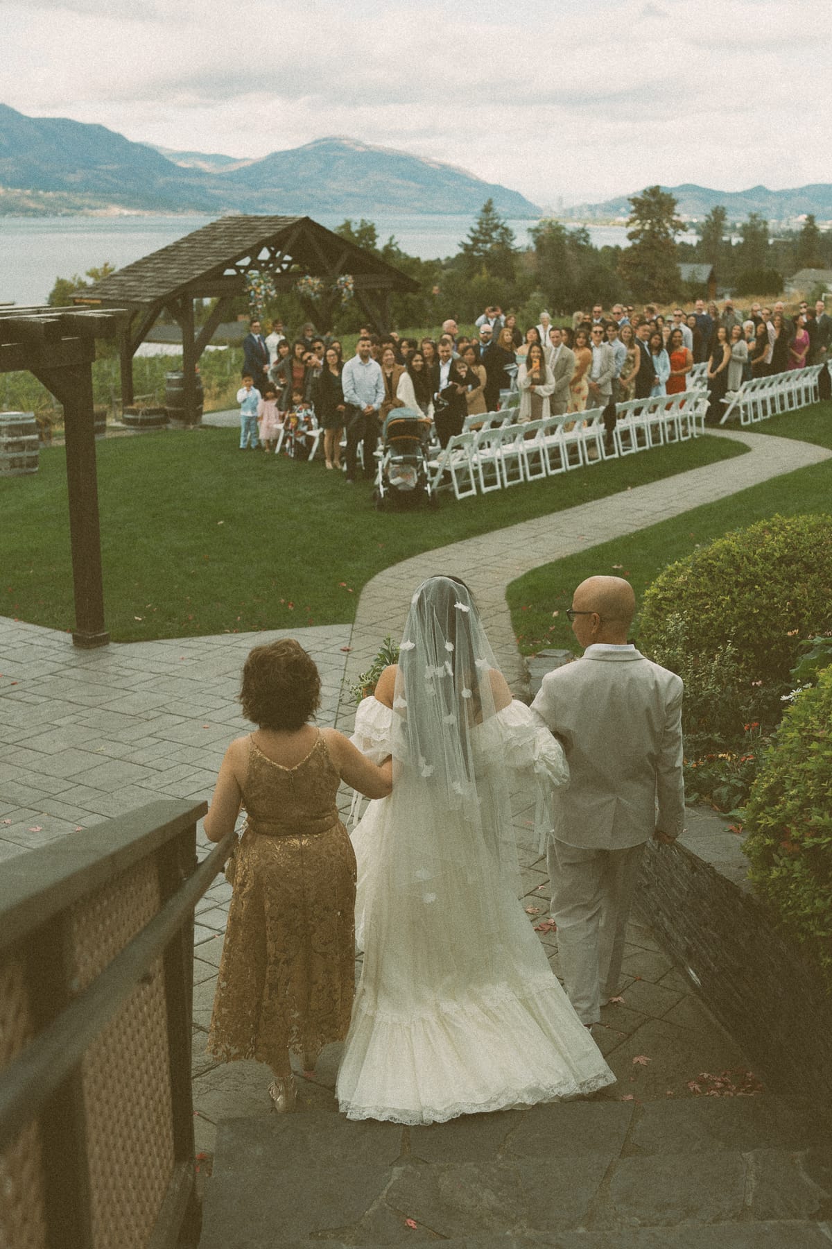 The processional toward the pergola as Nina and her parents approach the seated guests and lake