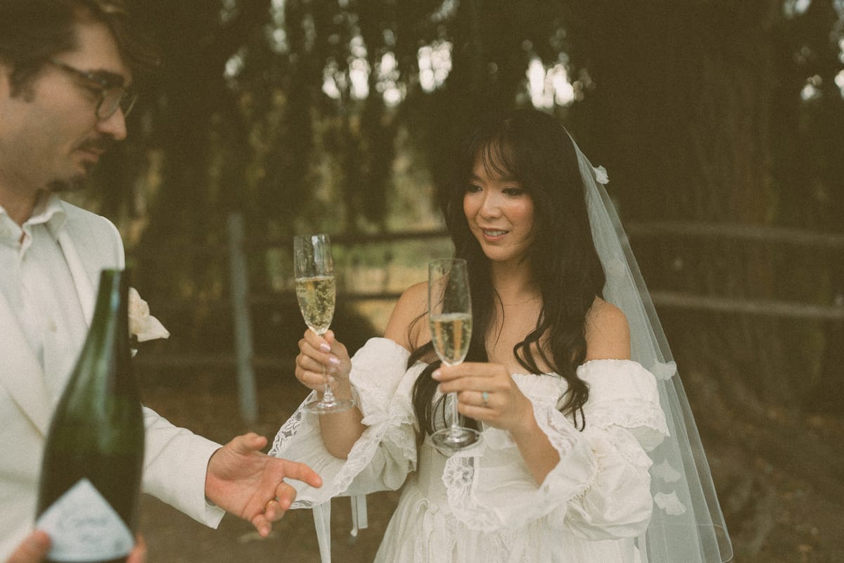 Nina and Brandon toasting with sparkling wine by the willow