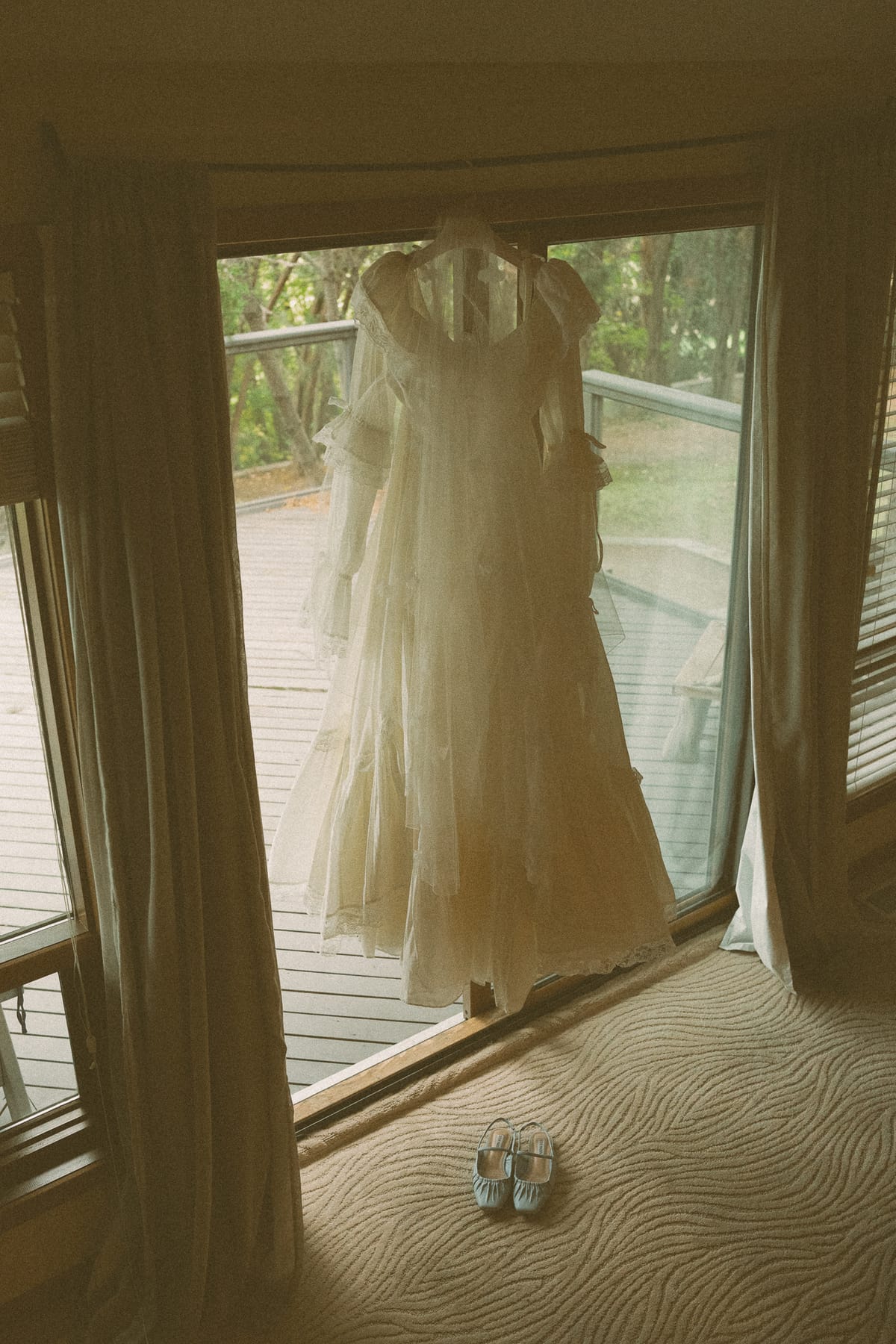 Nina's tiered vintage gown hanging in the window with her blue shoes below