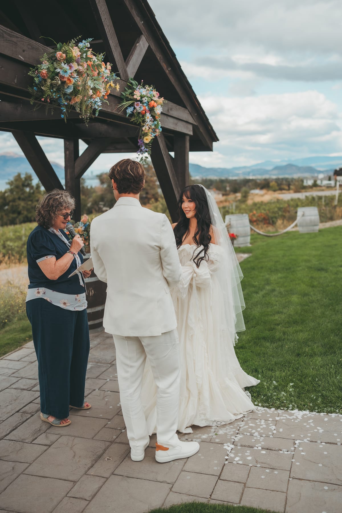 Nina and Brandon at the flower-topped pergola with their officiant during the ceremony