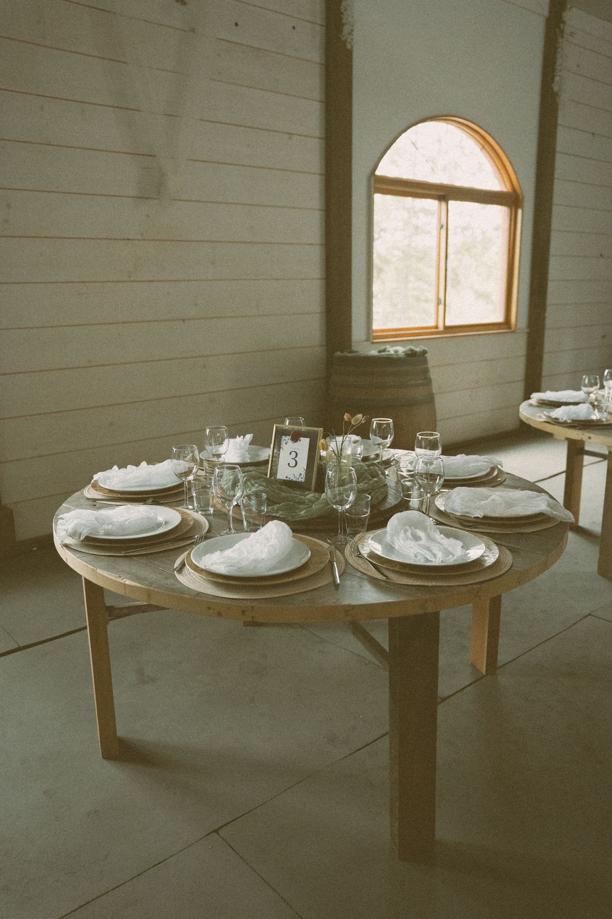 Place settings laid out on a wooden farm table for the reception