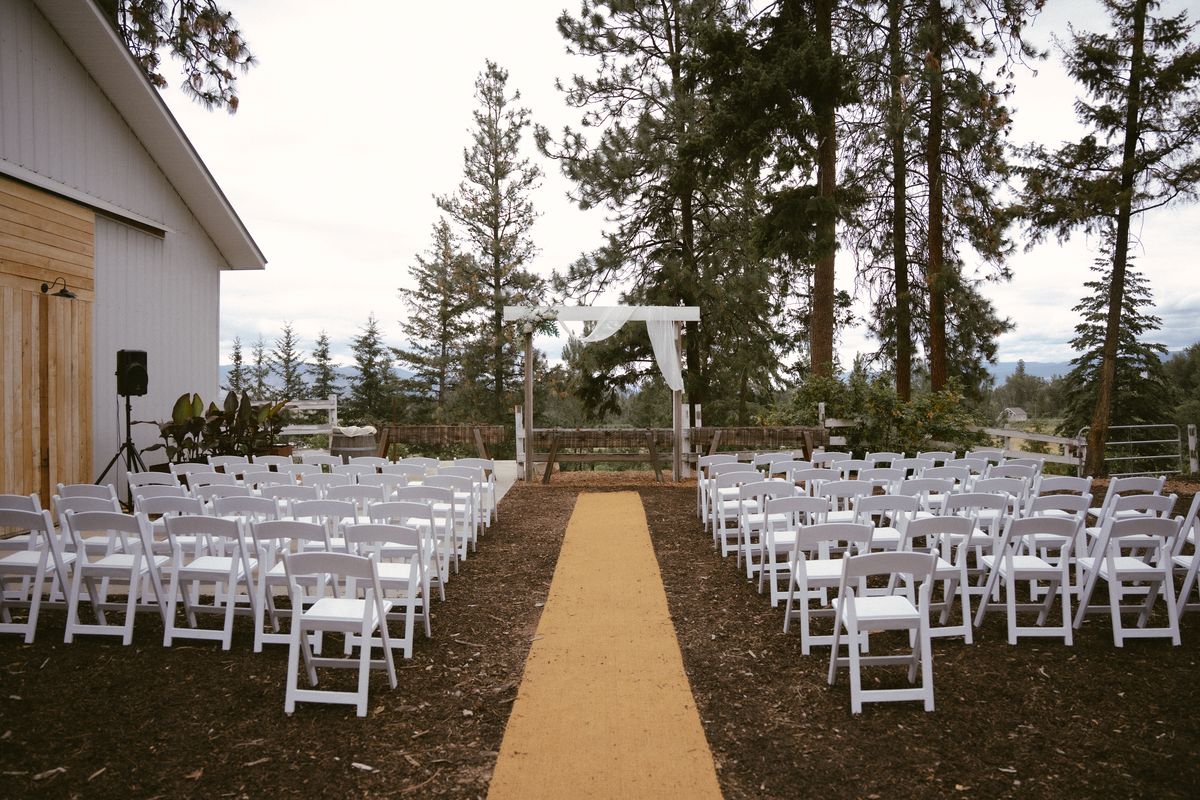 Ceremony chairs and aisle set before the white barn at Three Little Birds Farm