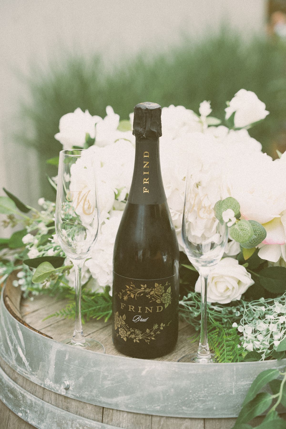 Champagne bottle and white florals styled on a wine barrel