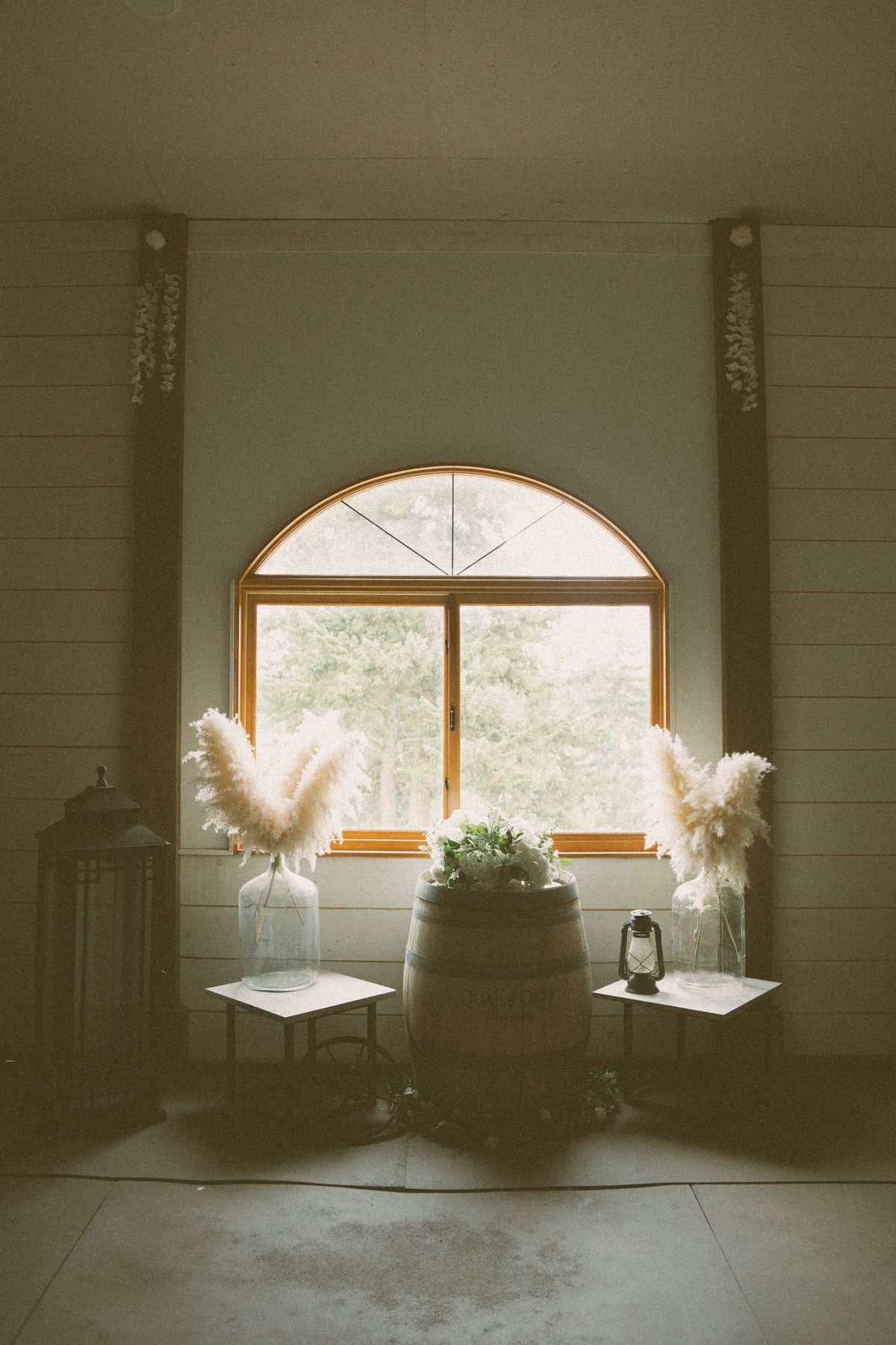 Arched window styled with florals inside the barn