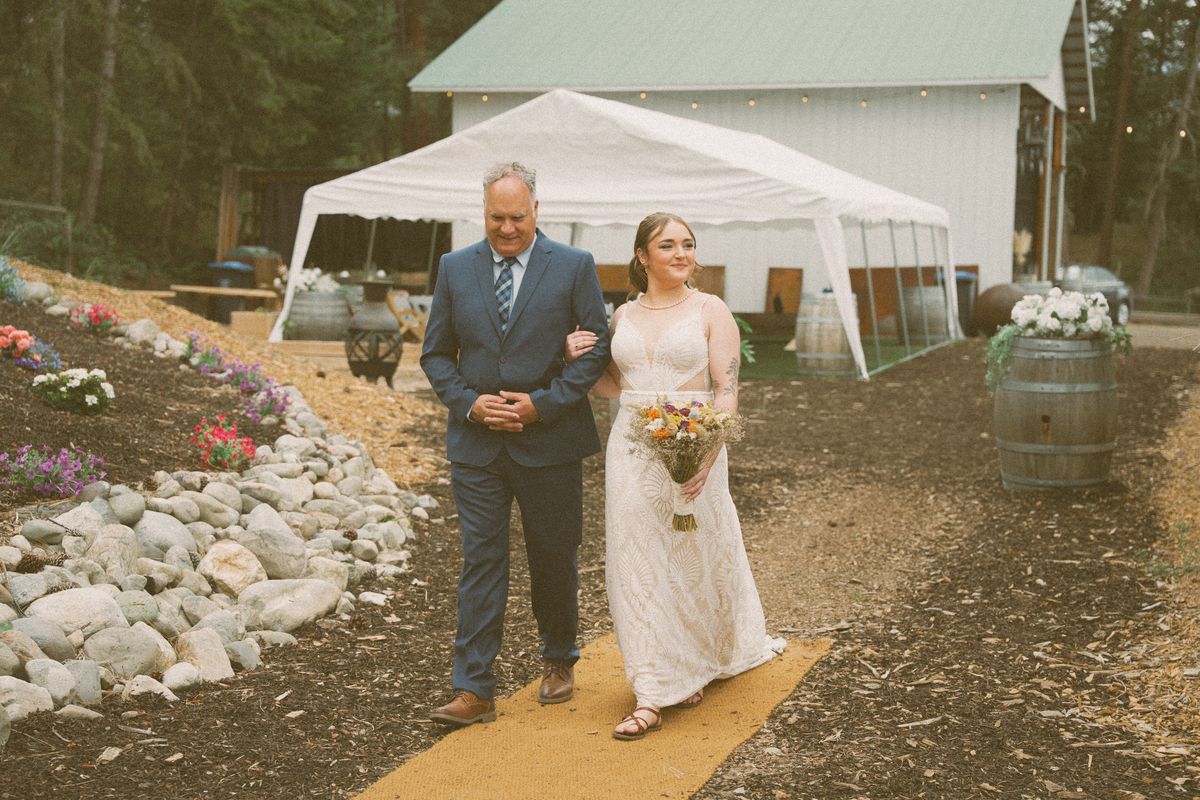 Bride walking in on her father's arm toward the ceremony tent
