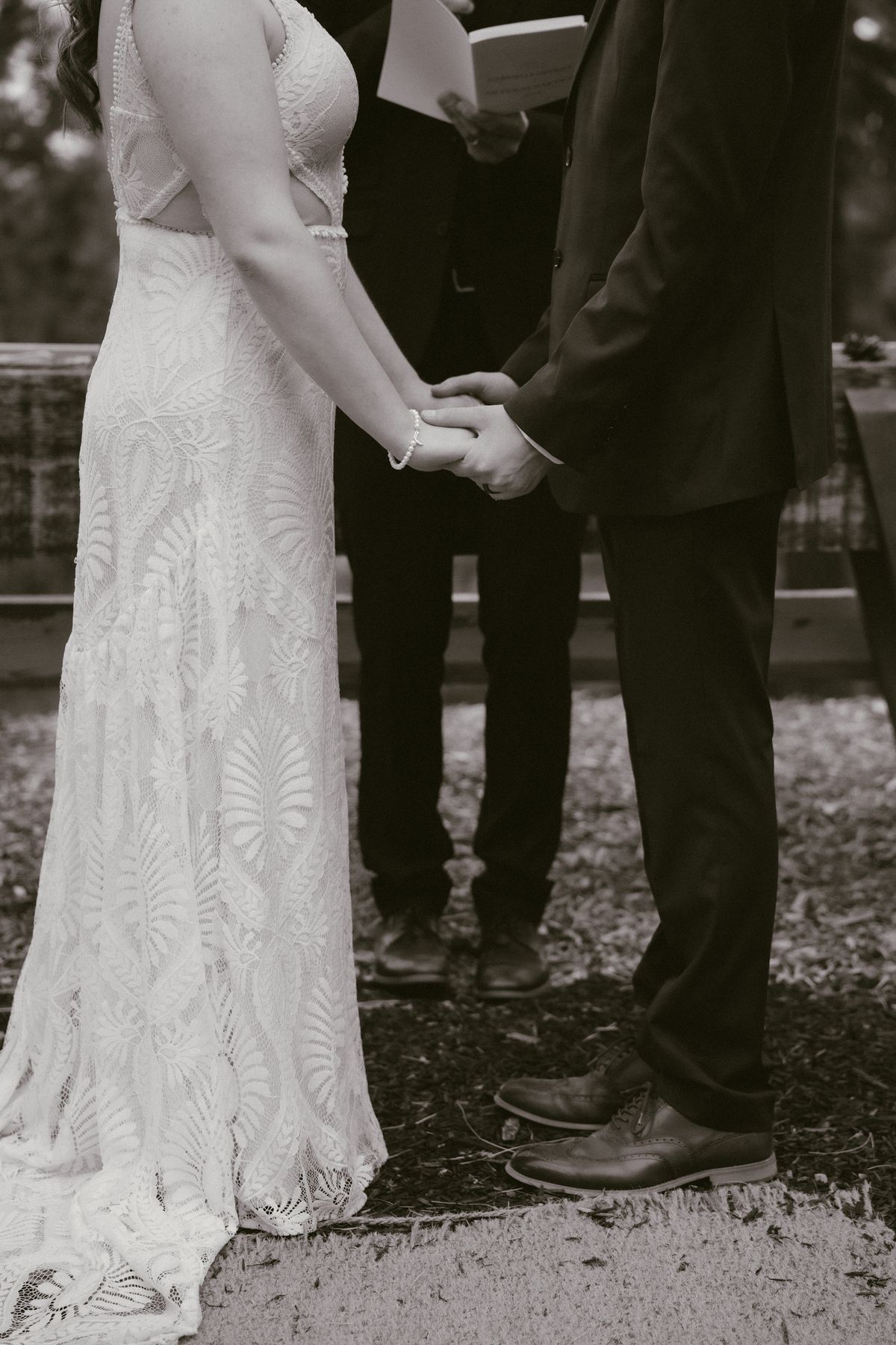 Black and white of the couple holding hands during their vows