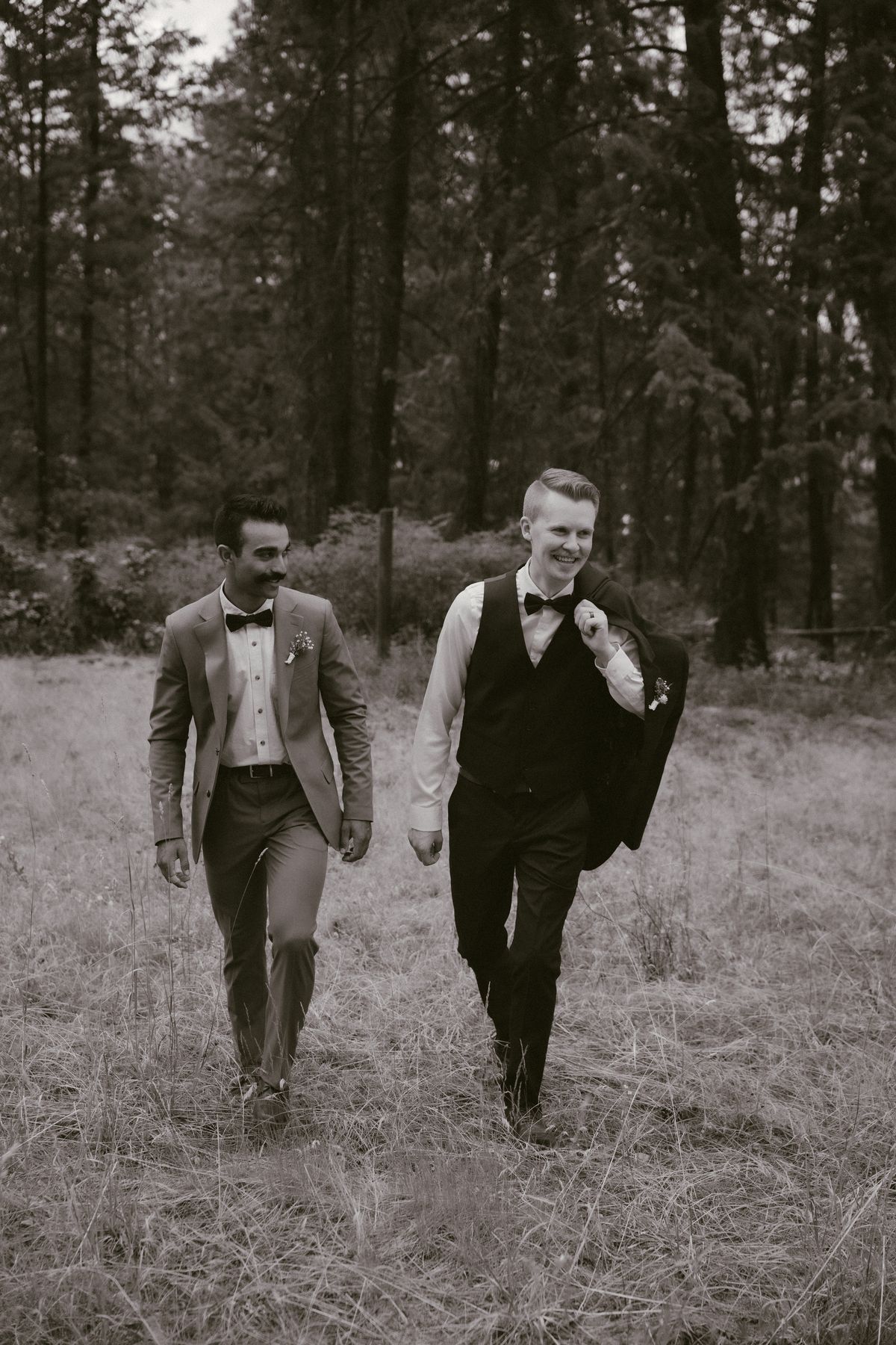 Black and white of the couple walking playfully through the field