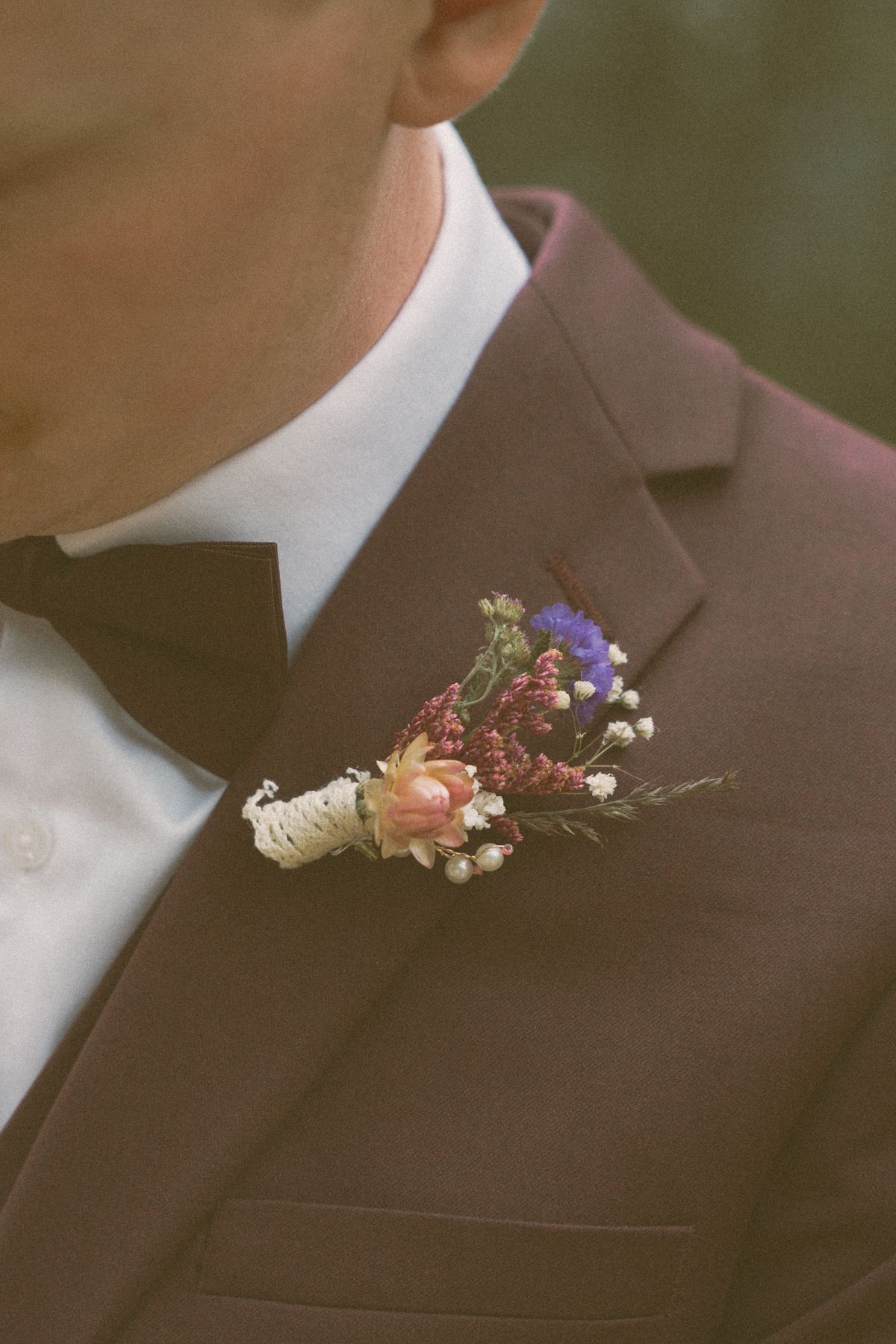Detail of the groom's wildflower boutonniere on his burgundy lapel
