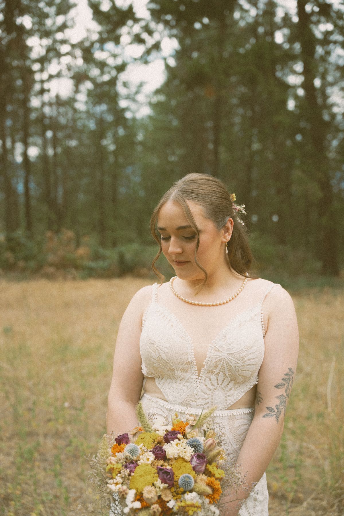Bride holding her bright wildflower bouquet among the trees