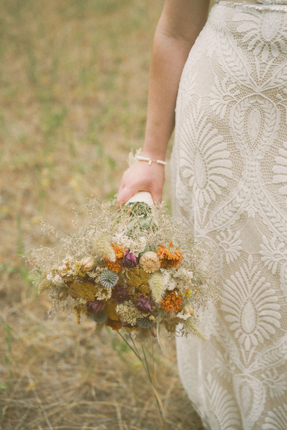 Detail of the bride's hand resting on her gown beside her bouquet