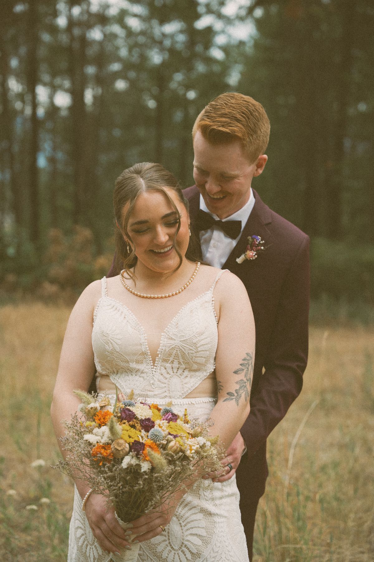 Groom kissing the bride's head as she holds her bouquet