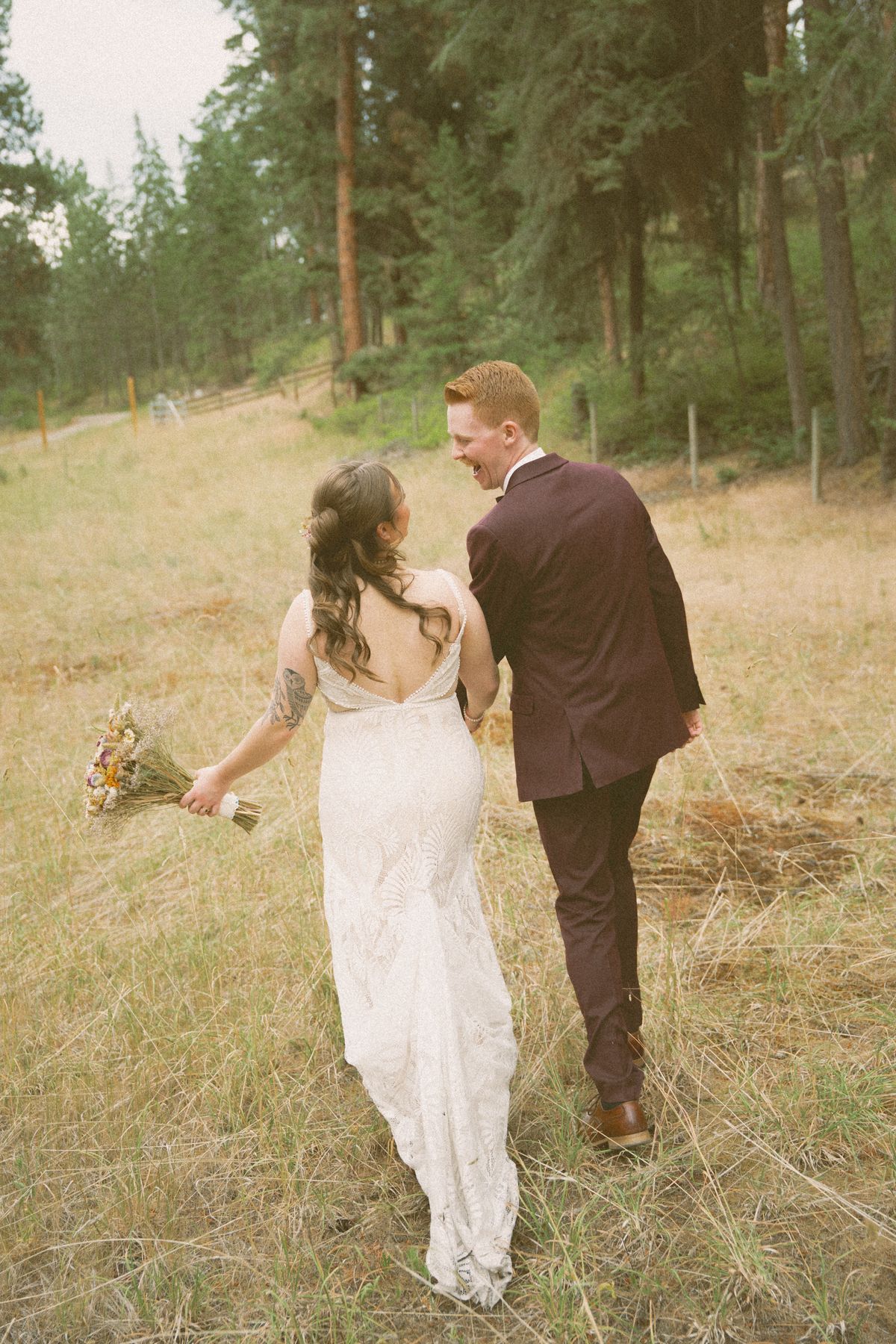 The couple walking through the field, the bride glancing back
