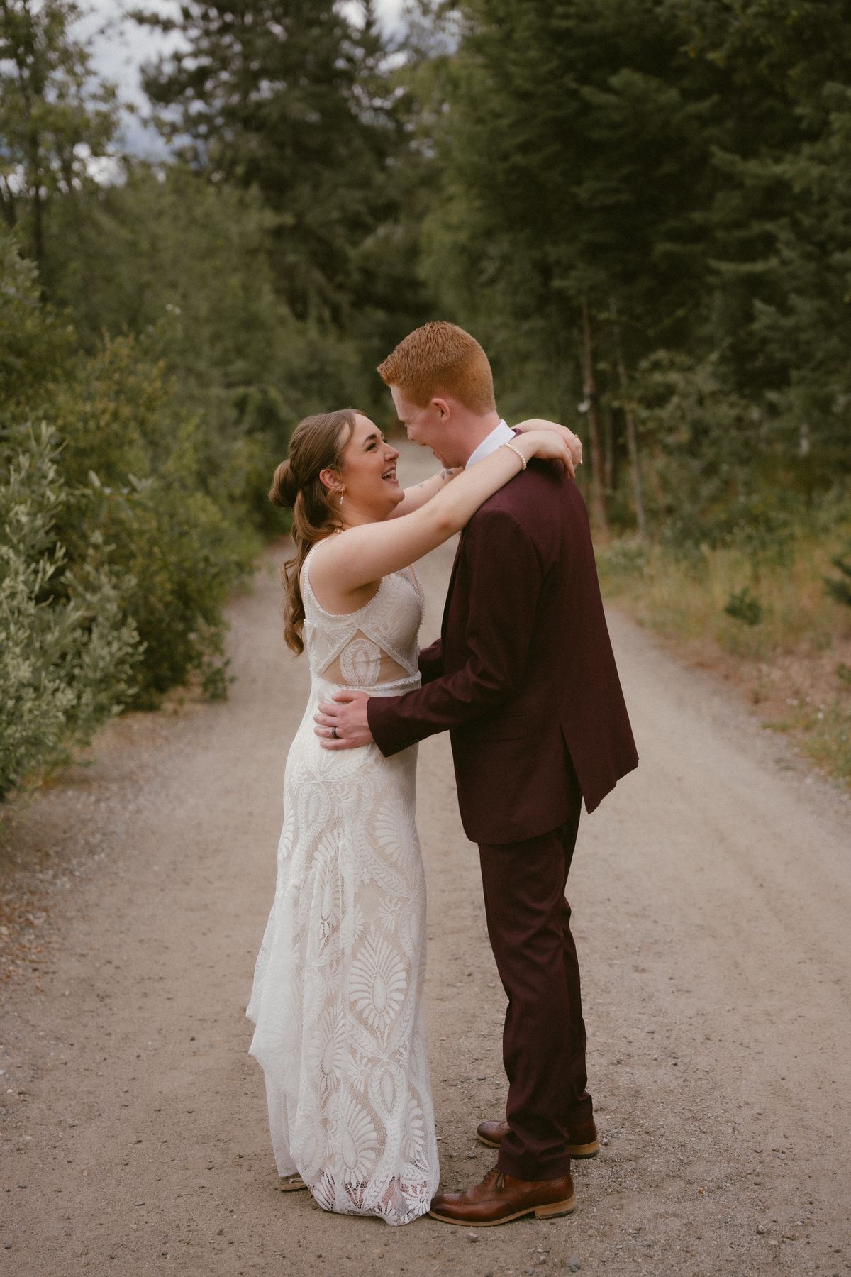 The couple touching foreheads on the tree-lined path