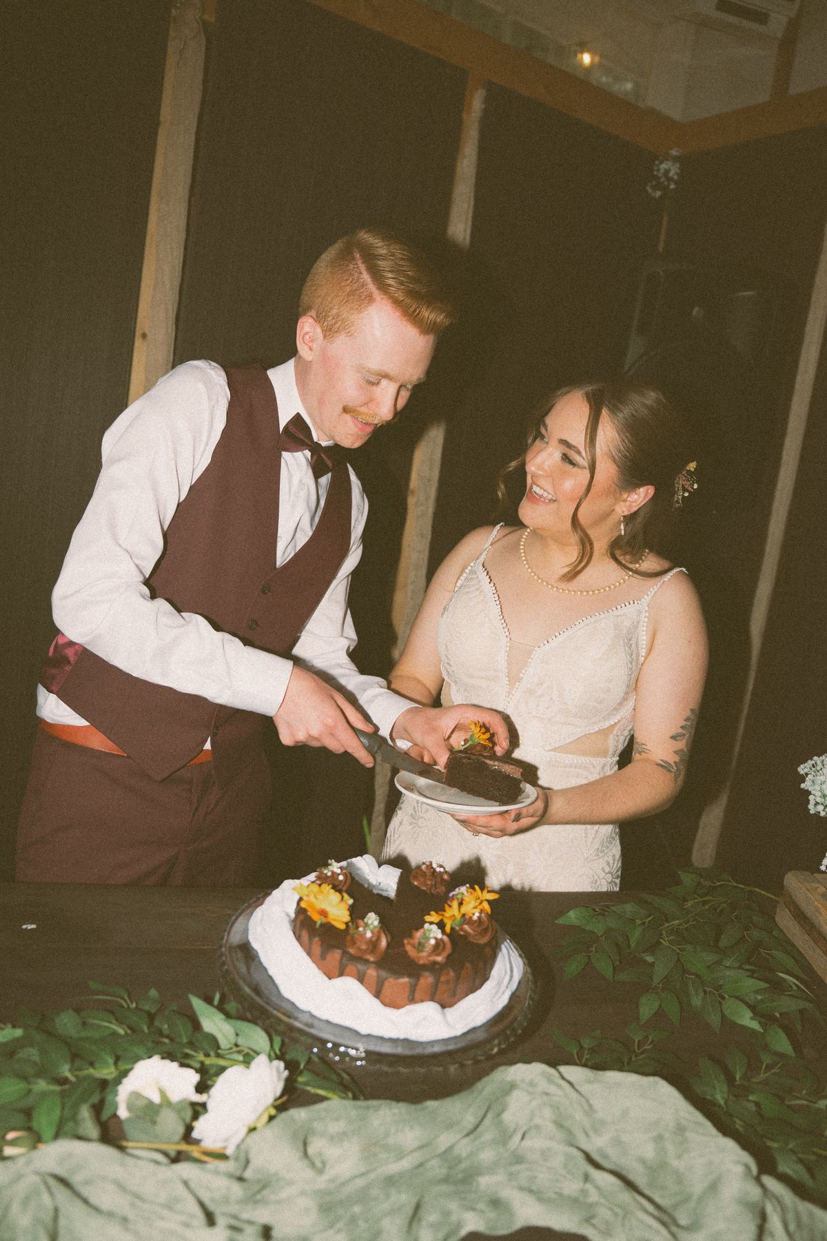 Bride and groom cutting their flower-topped cake at the reception
